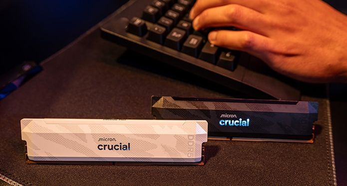 兩個 Crucial DDR5 Pro OC CL32 模組並列在桌上,旁邊是某人使用鍵盤。