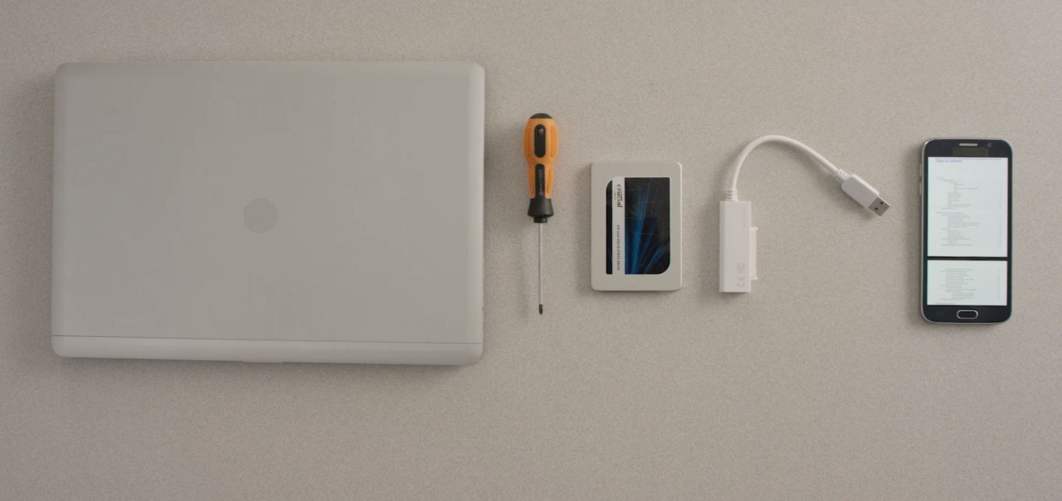 一台筆記型電腦、Crucial SSD、螺絲起子及手機上的電腦使用者手冊,一併陳列在桌面上