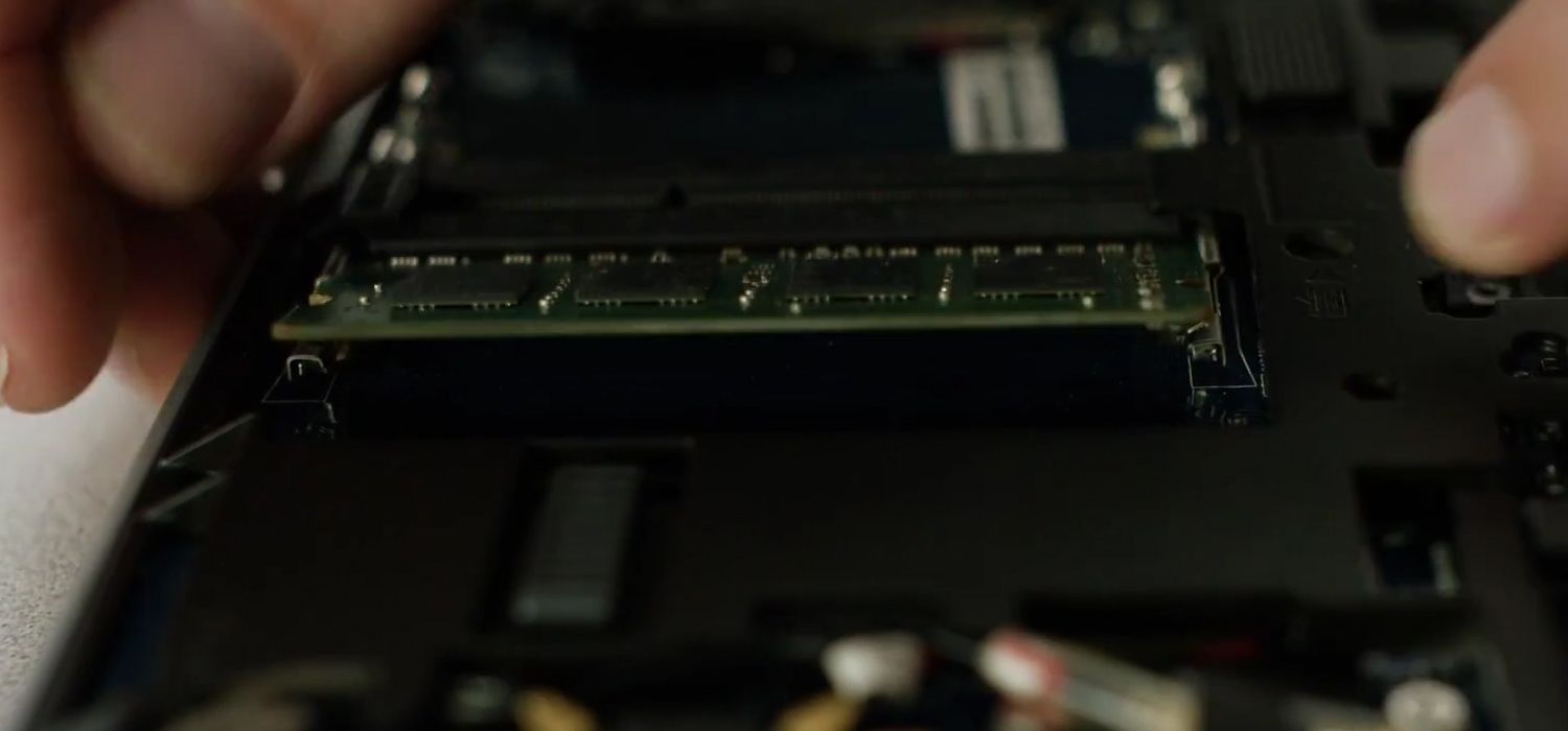 某人鬆開 Crucial RAM 模組側邊固定夾後,自筆電中移除。